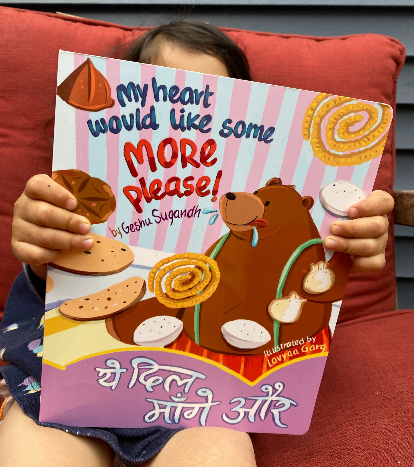 Front cover of the bilingual board book My Heart Would Like Some More, Please! featuring an Indian tea party with snacks and characters