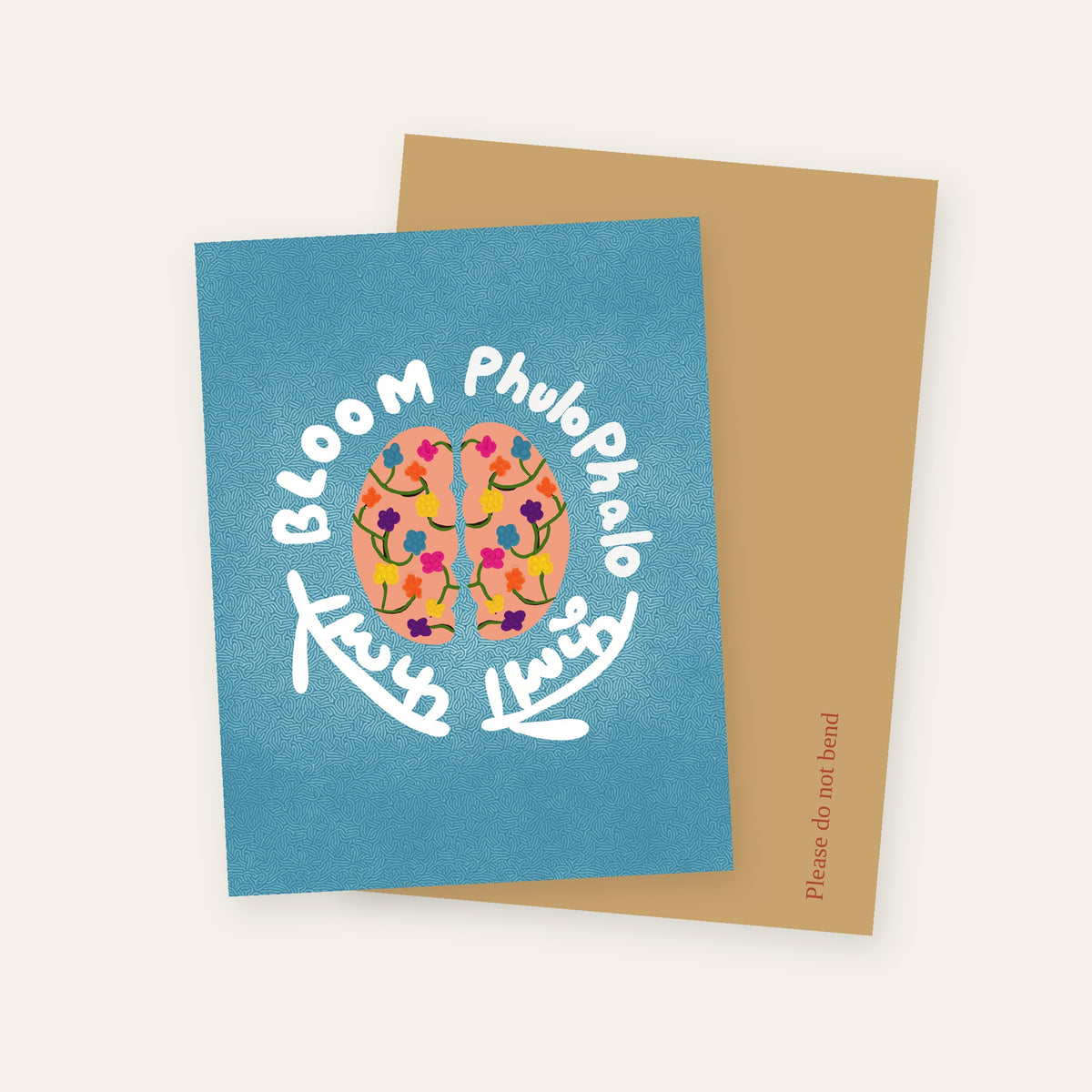 Brain Bloom greeting card showing a brain filled with flowers, circled by Bloom and Phulo Phalo in English and Devanagari, with its kraft mailer.