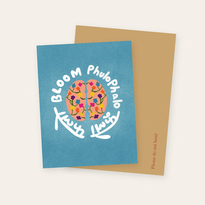 Brain Bloom greeting card showing a brain filled with flowers, circled by Bloom and Phulo Phalo in English and Devanagari, with its kraft mailer.