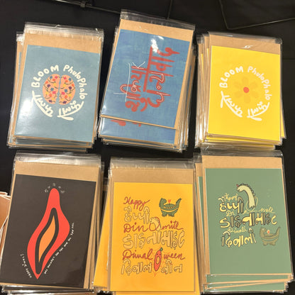 Stacks of all six Type Storytelling greeting cards in clear sleeves with kraft mailers on a black table.