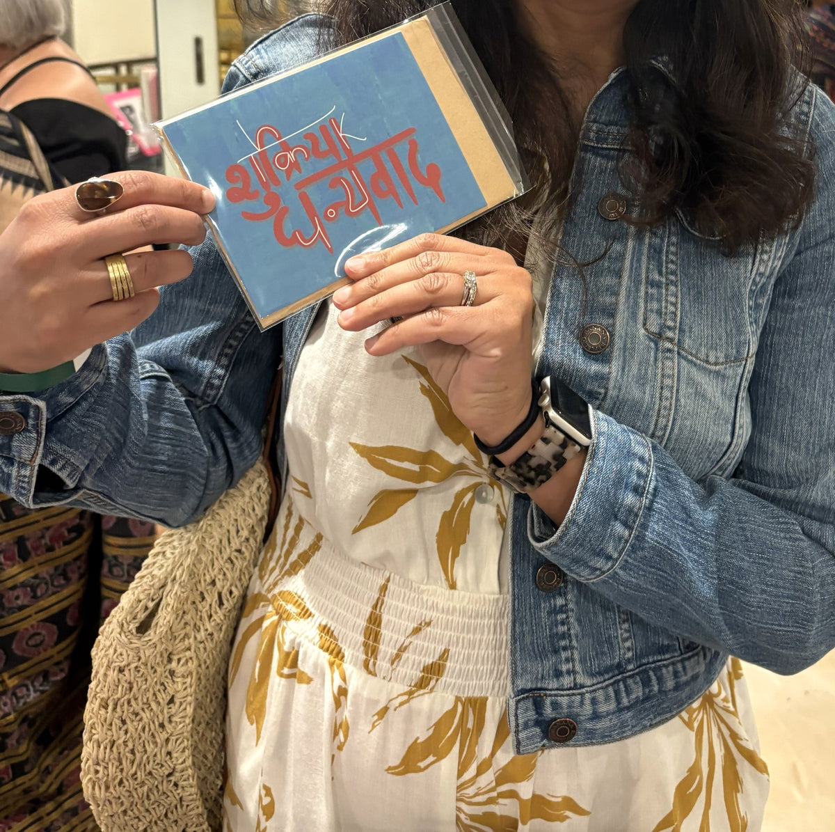 A visitor at the Chicago Indian Literature Festival holding the Shukriya Dhanyavad thank you card.