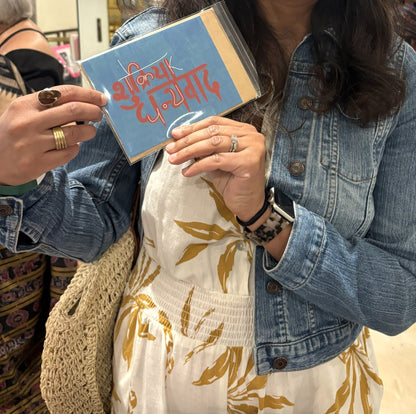 A visitor at the Chicago Indian Literature Festival holding the Shukriya Dhanyavad thank you card.